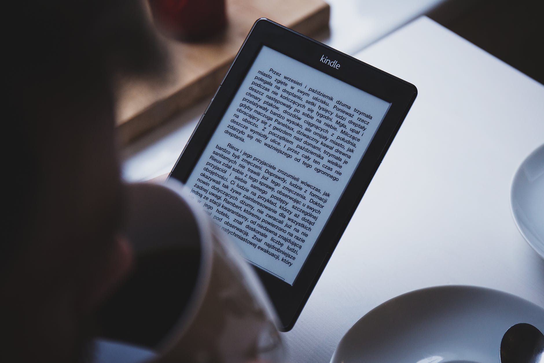 person using e book reader while drinking coffee
