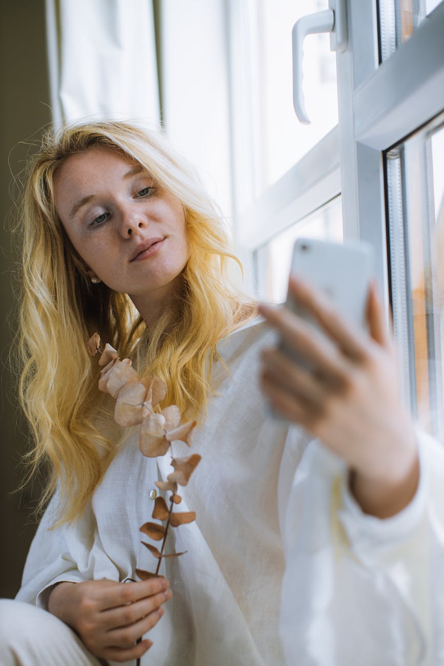 woman in white long sleeve shirt holding a smartphone